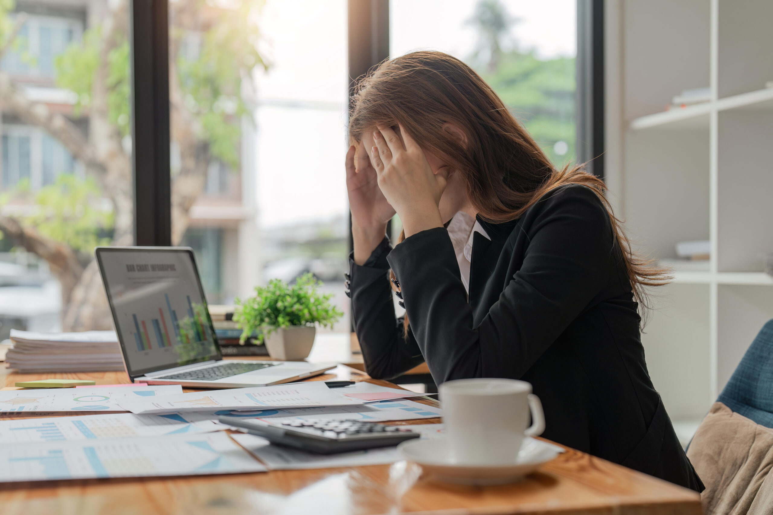 Stress, anxiety and burnout with a business woman at work using a laptop while suffering from a headache