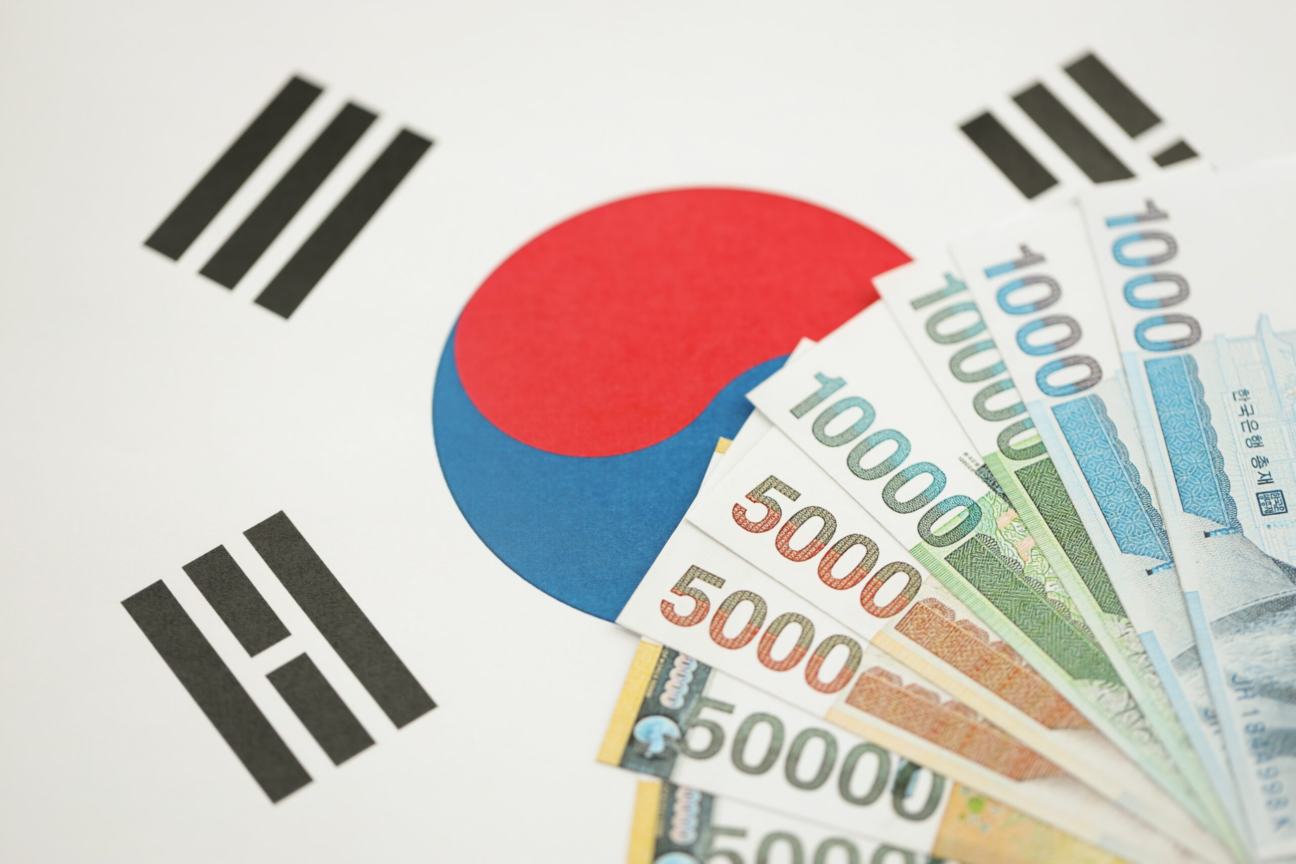 South Korean won money bills in big amount lies on South Korea flag close up
