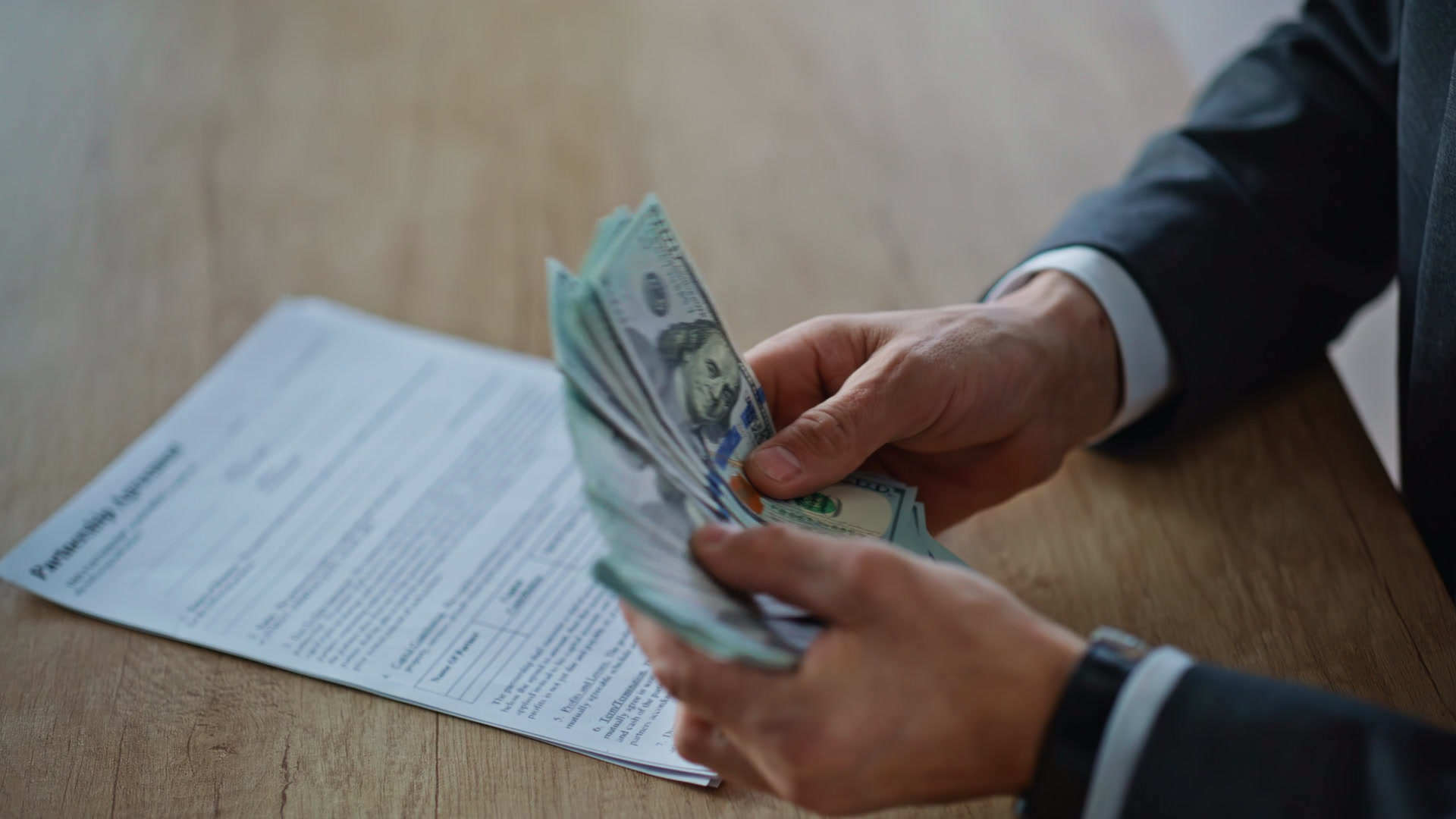 47678660_MotionElements_boss-hands-counting-salary-at-wooden-desk-closeup-vimage-a-0268